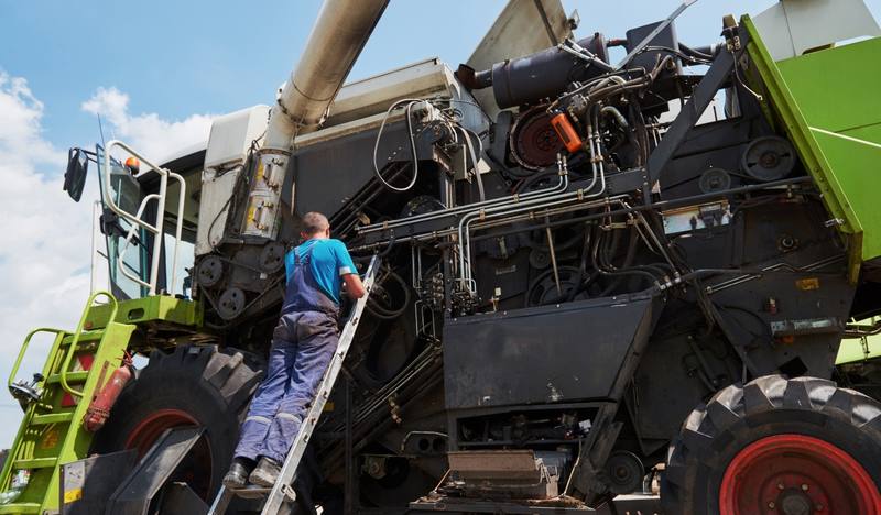combine-machine-service-mechanic-repairing-motor-outdoors