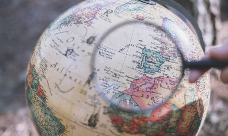 person-with-magnifying-glass-looking-globe