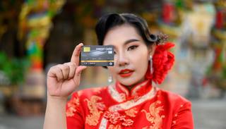 selective-focus-credit-card-hand-asian-beautiful-woman-wearing-cheongsam-smiling-poses-show-shrine-chinese-new-year