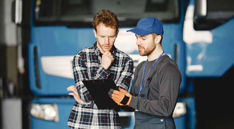 two-guys-talking-about-work-work-garage-near-truck-transfer-documents-with-goods