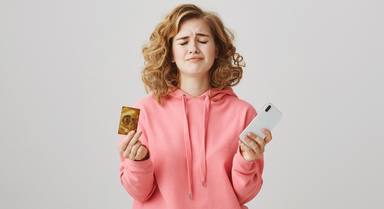 upset-curly-haired-girl-frowning-lacking-money-bank-account-hold-mobile-phone