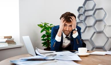 upset-young-businessman-sitting-workplace-office-background