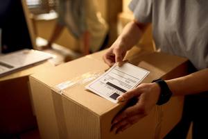 wp-5514e42d8143ff1c-closeup-courier-attaching-address-label-package-while-working-office