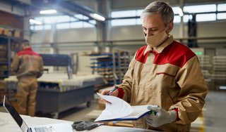 wp-680e583bc9e55c90-male-carpenter-wearing-face-mask-while-going-through-paperwork-workshop