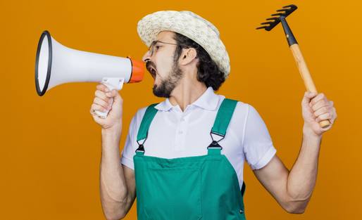 wp-6f892ede8f0c77a4-young-bearded-gardener-man-wearing-jumpsuit-hat-holding-mini-rake-shouting-megap