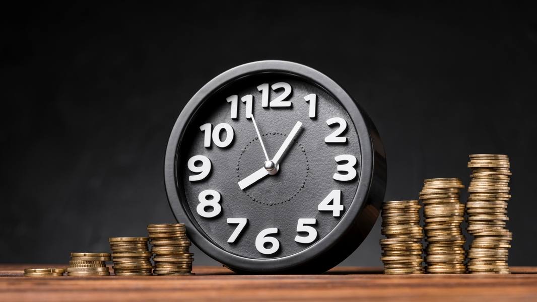 wp-a9bec136c8ae555d-round-clock-increasing-coins-wooden-desk-against-black-backdrop